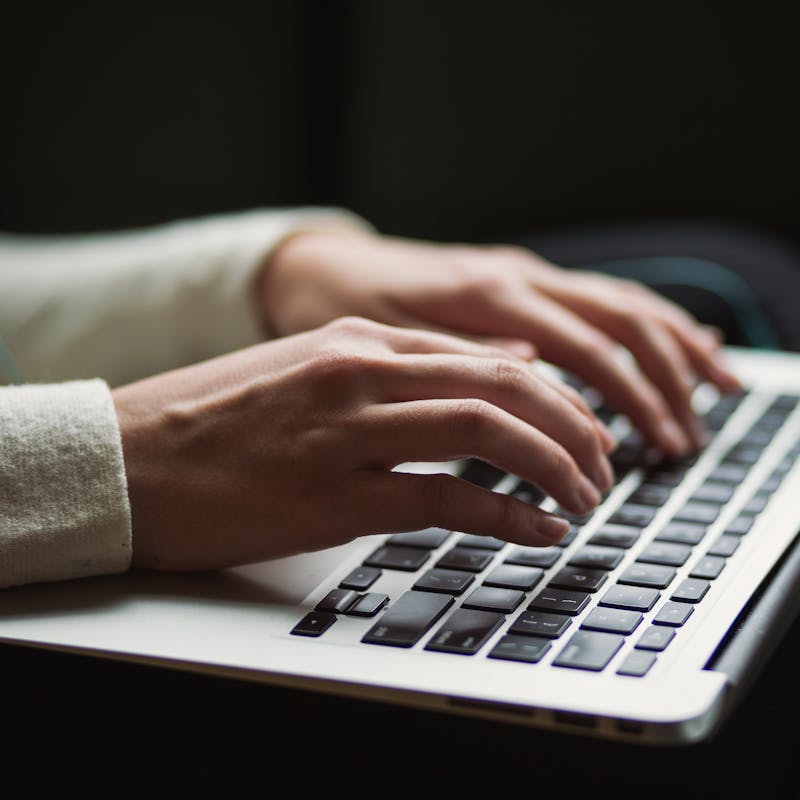 Nærmynd af kvennmanshöndum að pikka á lyklaborð í fartölvu