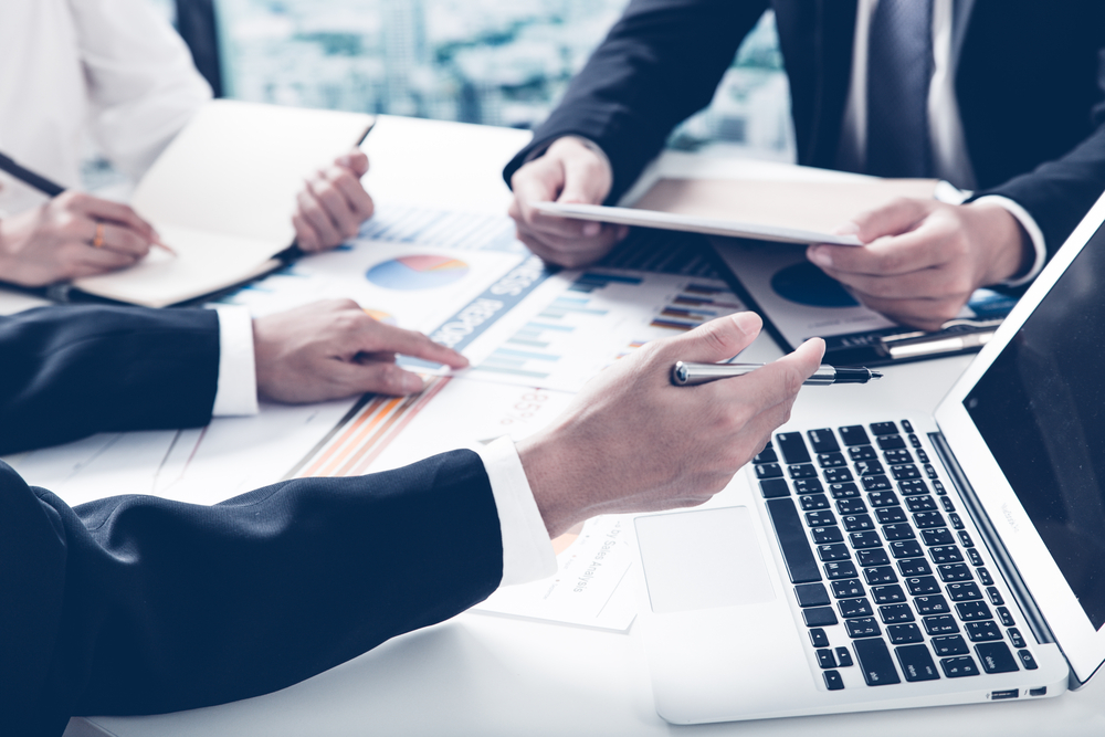 Nærmynd af jakkaklæddum mönnum við vinnu í ýmsum skjölum og gögnum