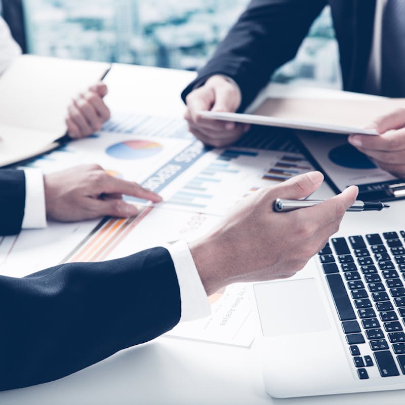 Nærmynd af jakkaklæddum mönnum við vinnu í ýmsum skjölum og gögnum