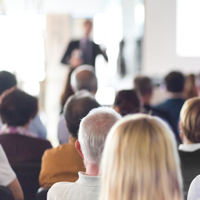 Ræðumaður heldur ræðu á viðskiptafundi, áhorfendur í ráðstefnusal