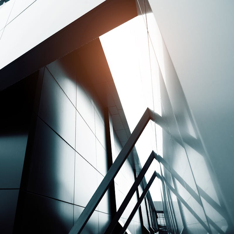 Abstrakt mynd af húsvegg, ljósbirta fellur á vegginn