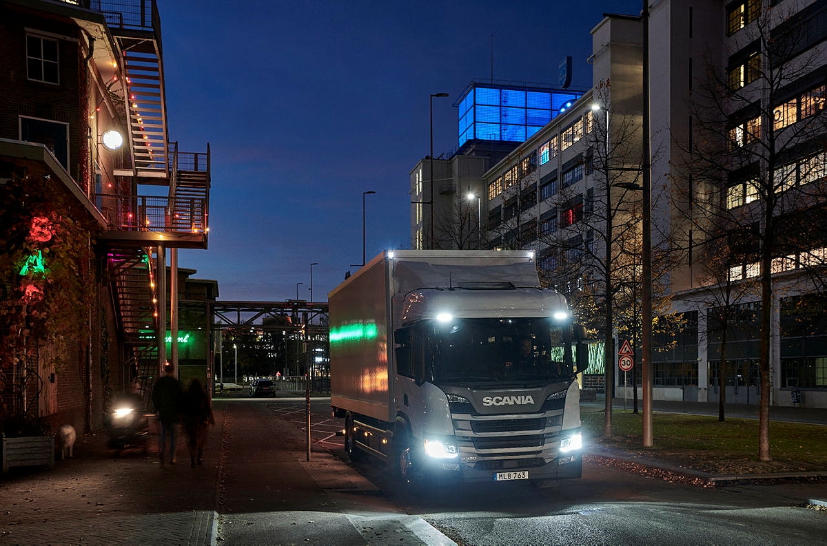 Scania truck delivering goods to restaurants at night.