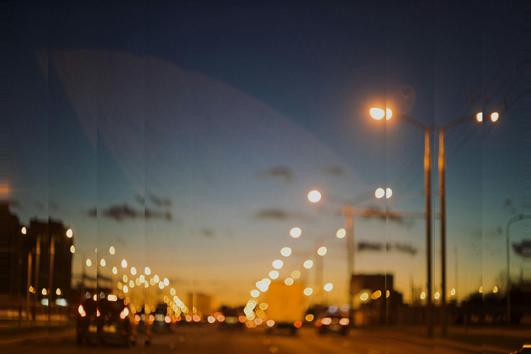Streetlights and taillights light up a highway for connected logistics providers driving into a city at twilight.