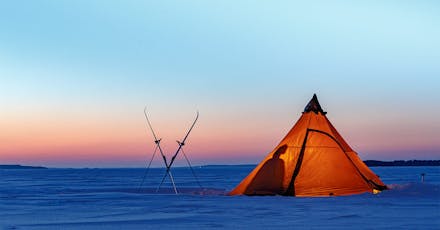 Teltta talvisessa maisemassa auringon laskisessa