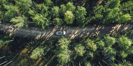 Aerial view road with car in green woods in Finland.