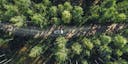 Aerial view road with car in green woods in Finland.