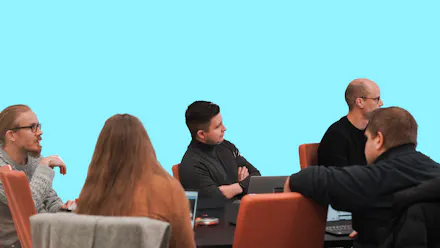 Viisi henkilöä ovat kokoontuneet pöydän ääreen tekemään teknistä arviota kohdeyrityksen ohjelmistoista.