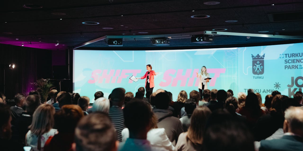 Puhuja pitämässä esitystä bisnesfestivaaleilla isolle yleisölle.