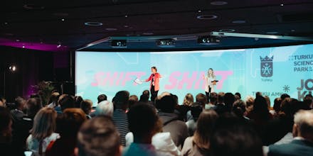 Puhuja pitämässä esitystä bisnesfestivaaleilla isolle yleisölle.