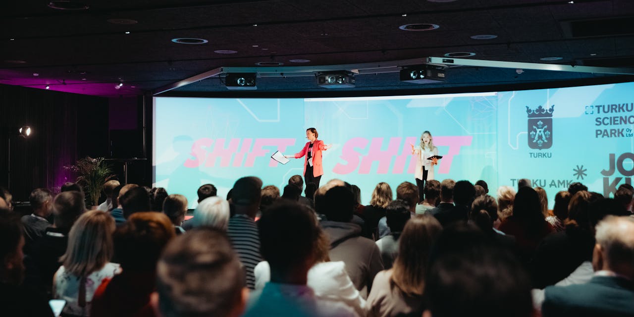 Puhuja pitämässä esitystä bisnesfestivaaleilla isolle yleisölle.