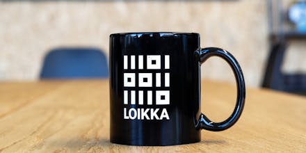 A coffee mug with Loikka's logo on table