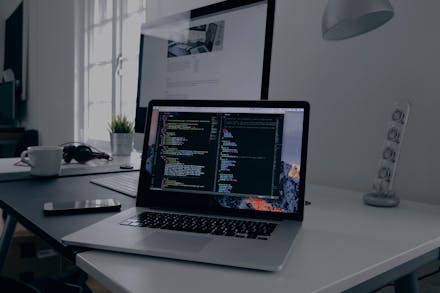 A laptop on a table, code on screen.