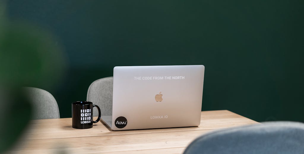 Kannettava tietokone vihreän seinän edessä, muki vieressä.