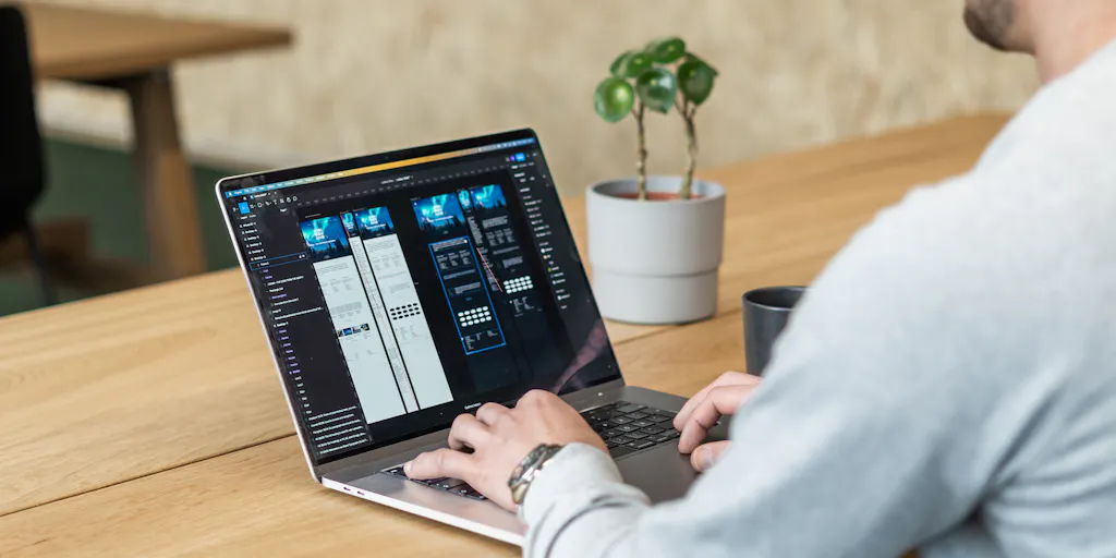 UI/UX -suunnittelija rakentaa ja suunnittelee verkkosivujaan Figmalla. Sovellus on auki suunnittelijan kannettavan tietokoneen näytöllä.