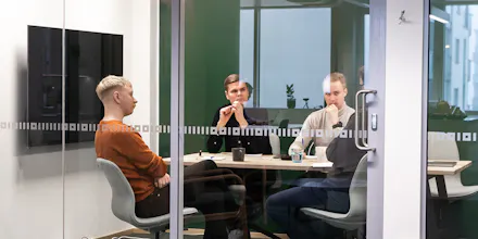 Neljä miestä istuvat kokouspöydän ääressä neuvotteluhuoneessa.