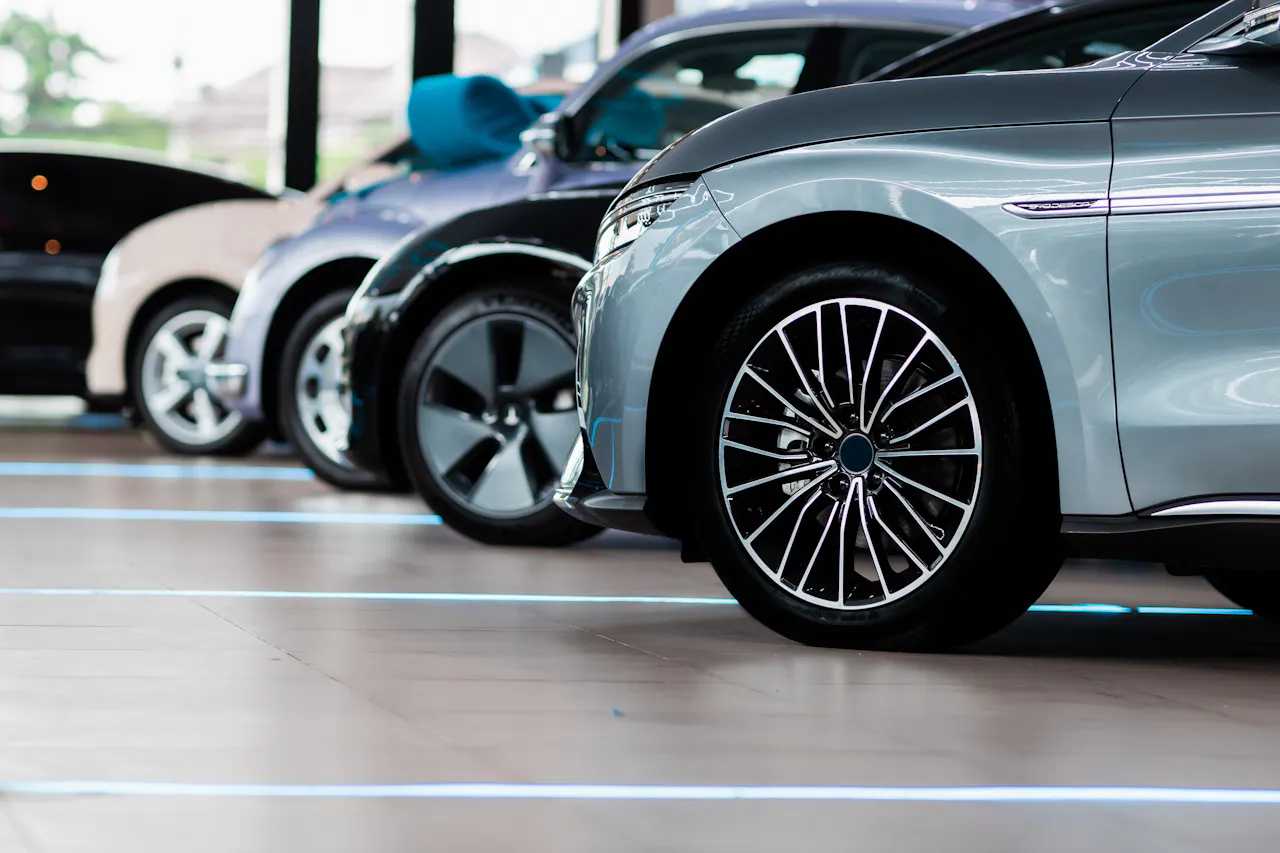 Kaunis autokaupan näyttelyhuone, jossa uudet autot ovat esillä ja myynnissä. Autot ovat näyttävästi rivissä puhtaan valkoisella lattialla odottamassa myyntiä.