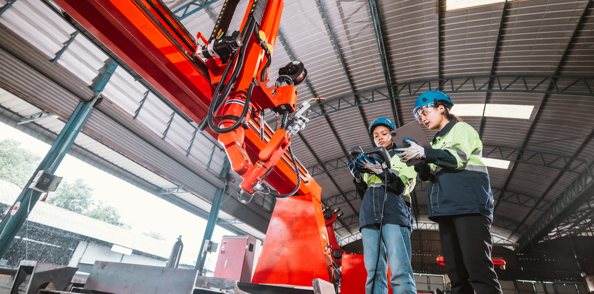 Two industrial workers using tablets to control machinery while wearing gloves
