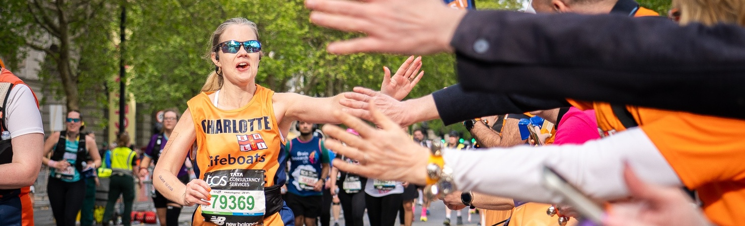 Cheering marathoner reaches out to high five spectators.
