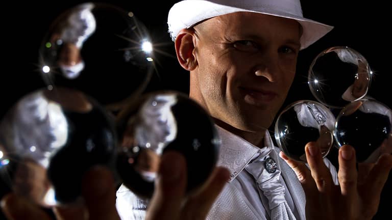 Walkact balanciert mit Kugel-Kontaktjonglage auf den Ellbogen.