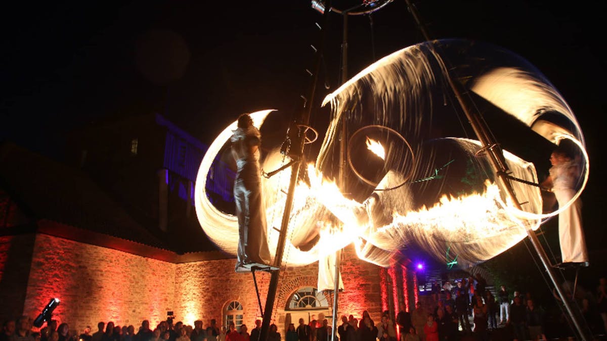 Fire show with aerial artistry on a scaffolding in front of an audience at an event in NRW.