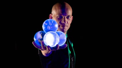 Contact juggler with four crystal balls in the hand.