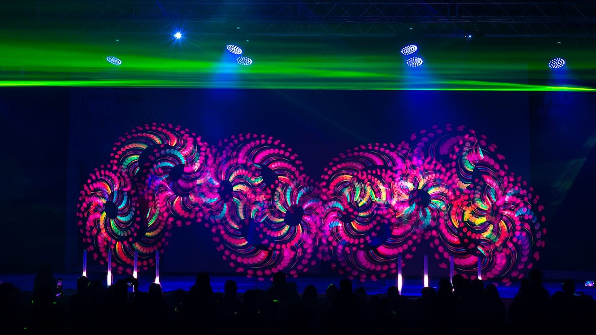 Bühnenshow mit Artisten, die mit LED-Lichtstäben jonglieren und dabei bunte Grafiken erzeugen.