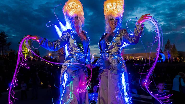 Zwei Stelzen Walkacts in leuchtenden silbernen Kostümen. 