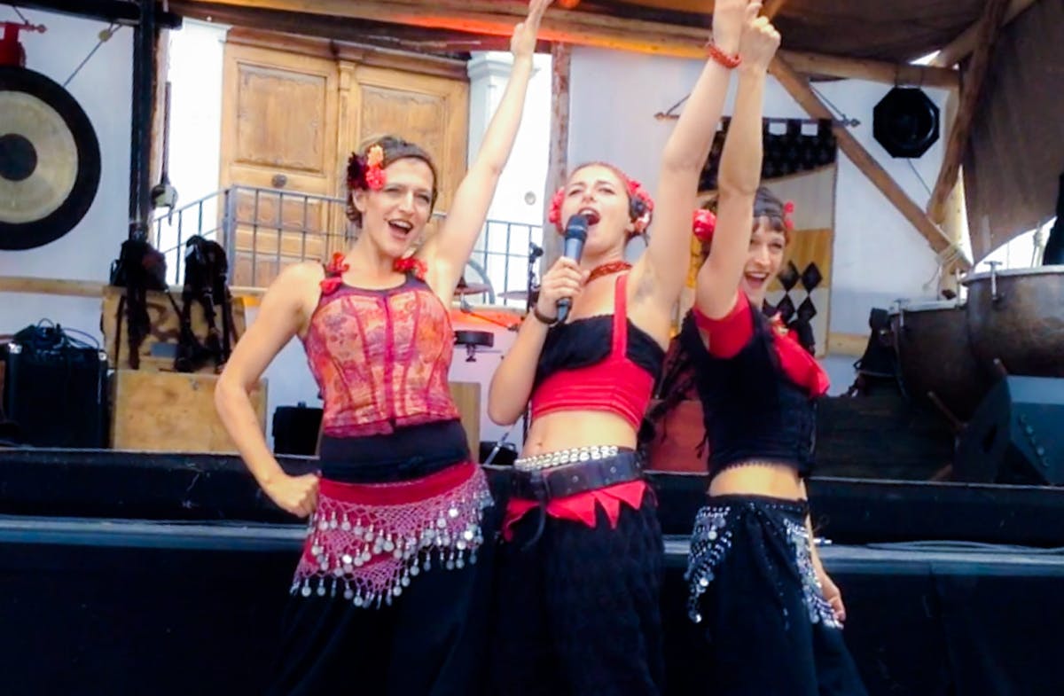 Streetshow with three circus girls pointing their hands in the air.