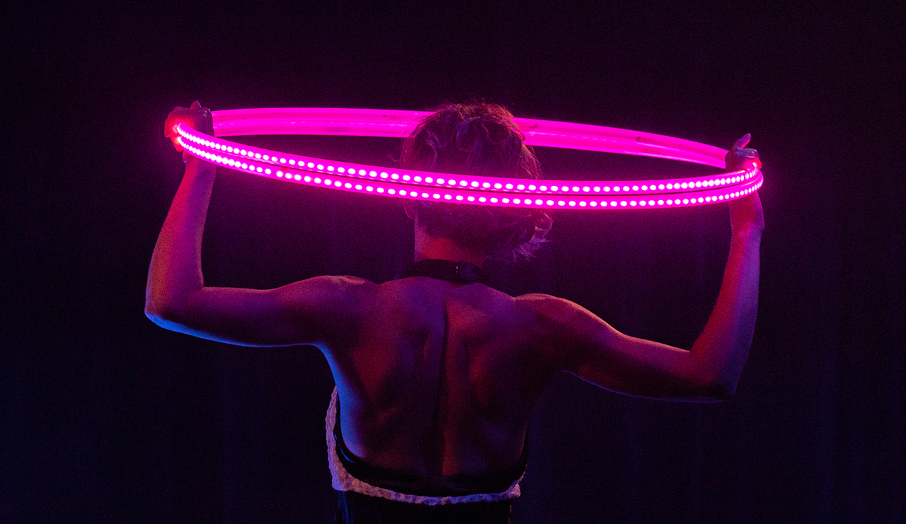 Showact mit vier leuchtenden LED-Multi-Hoops um den Körper der Artistin. 