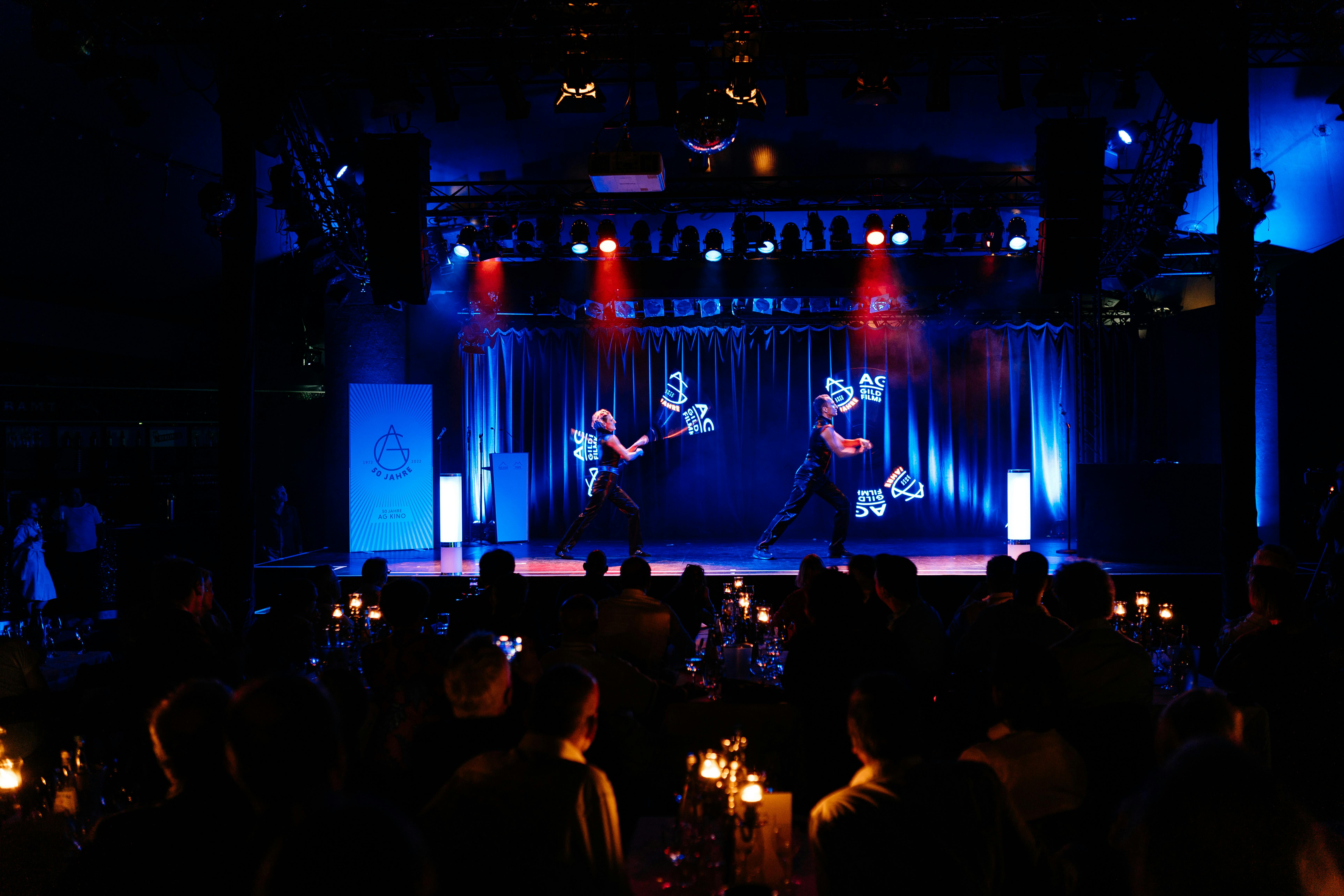 Two artists from LOOOOP playing a light show with LED pixel poi in a circus tent.