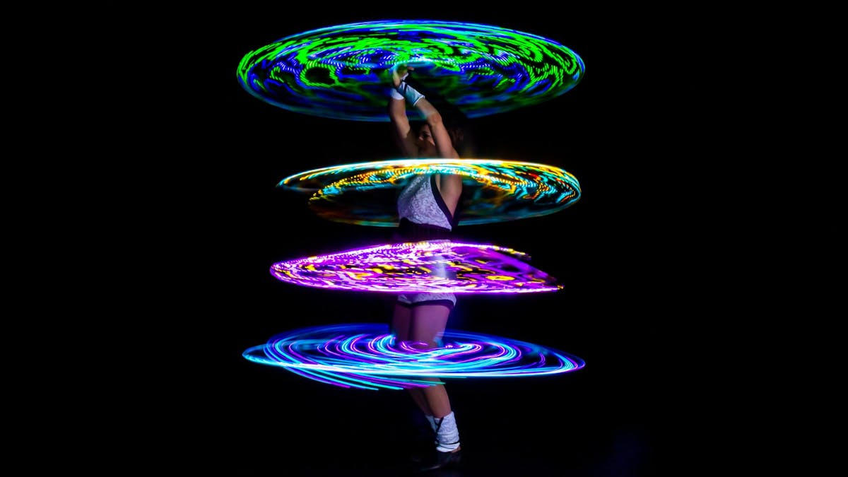 Showact mit vier leuchtenden LED-Multi-Hoops um den Körper der Artistin. 