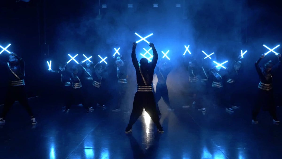 Breakdancer performing a light show, building a dance formation, lifting arms and crossing LED-tools. 