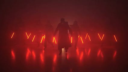 Dance formation holding red LED-Tools in hands and performer with long coat in the foreground. 