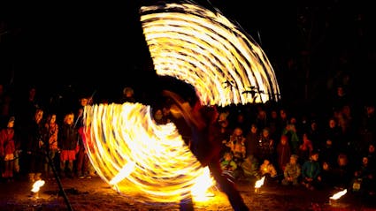 Fireshow with performer, who is swinging firepoi. 