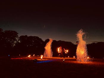 Feuershow am See bei Nacht mit großem Funkeneffekt und Feuerjongleur.