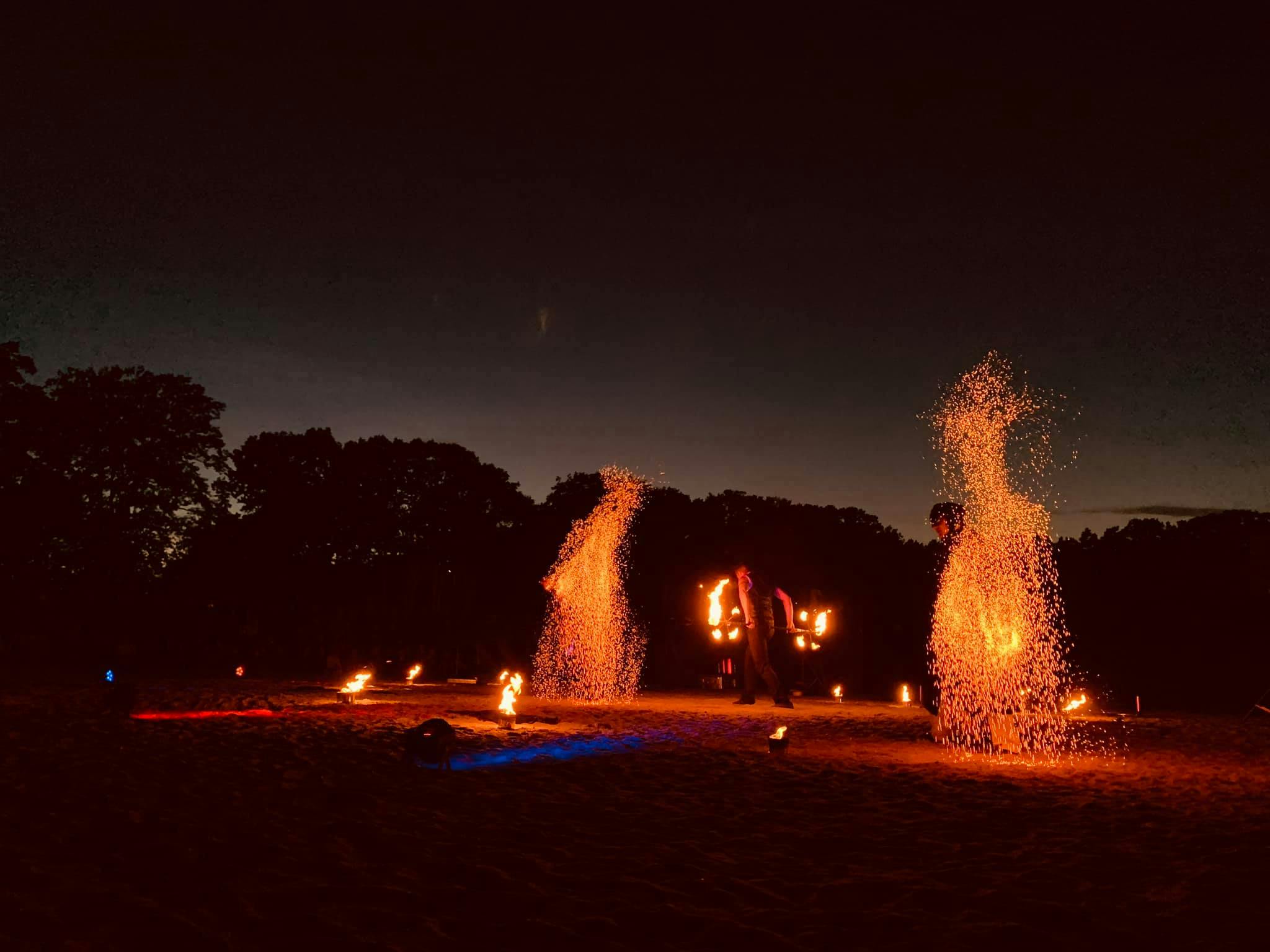 Feuershow am See bei Nacht mit großem Funkeneffekt und Feuerjongleur.