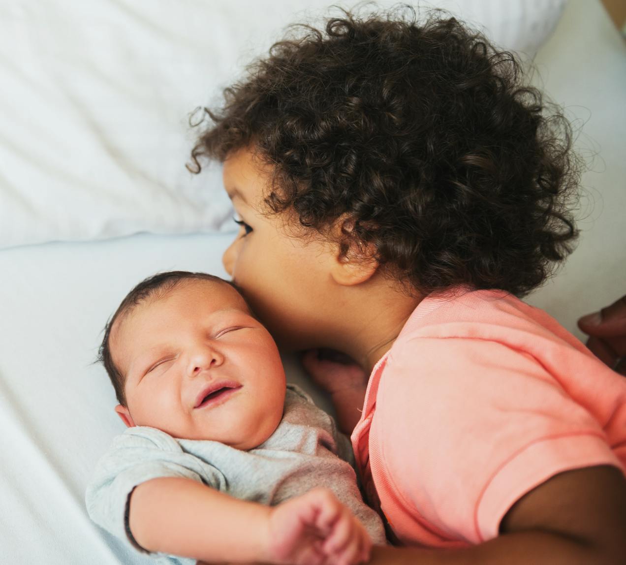 child kissing infant sibling