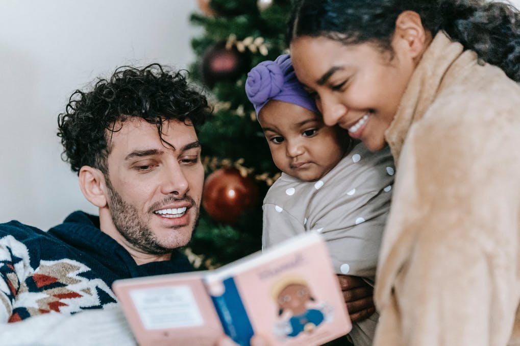 parents reading a board book to a baby