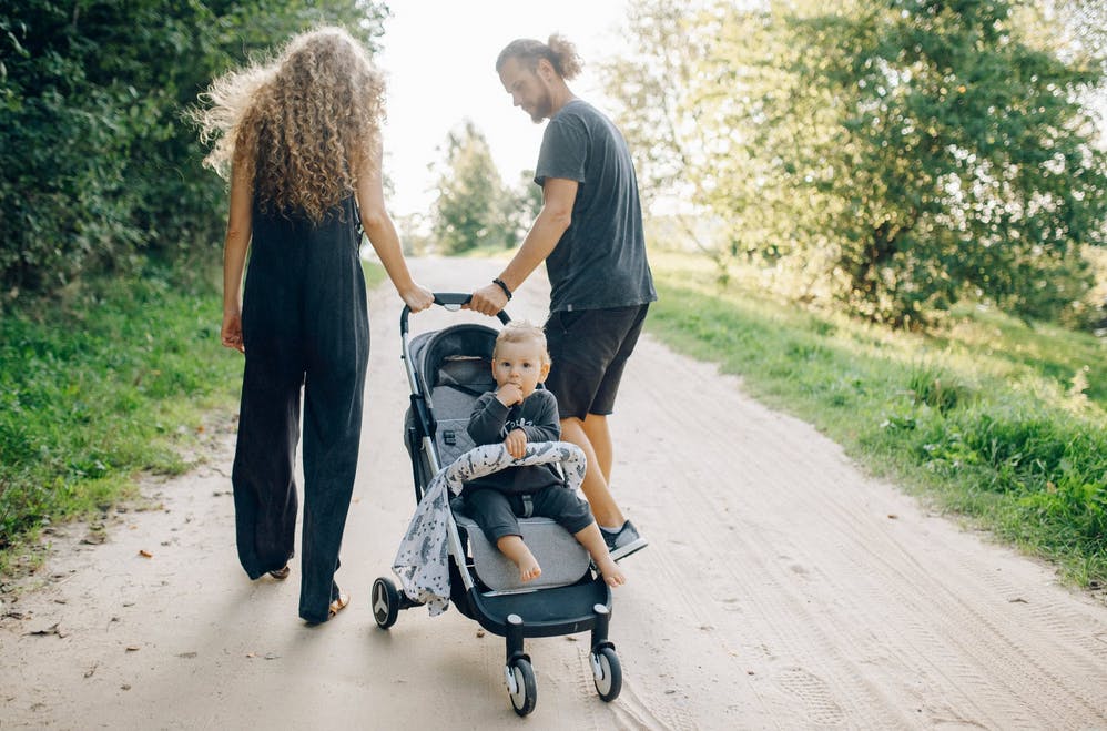 parents rolling a stroller down a country road