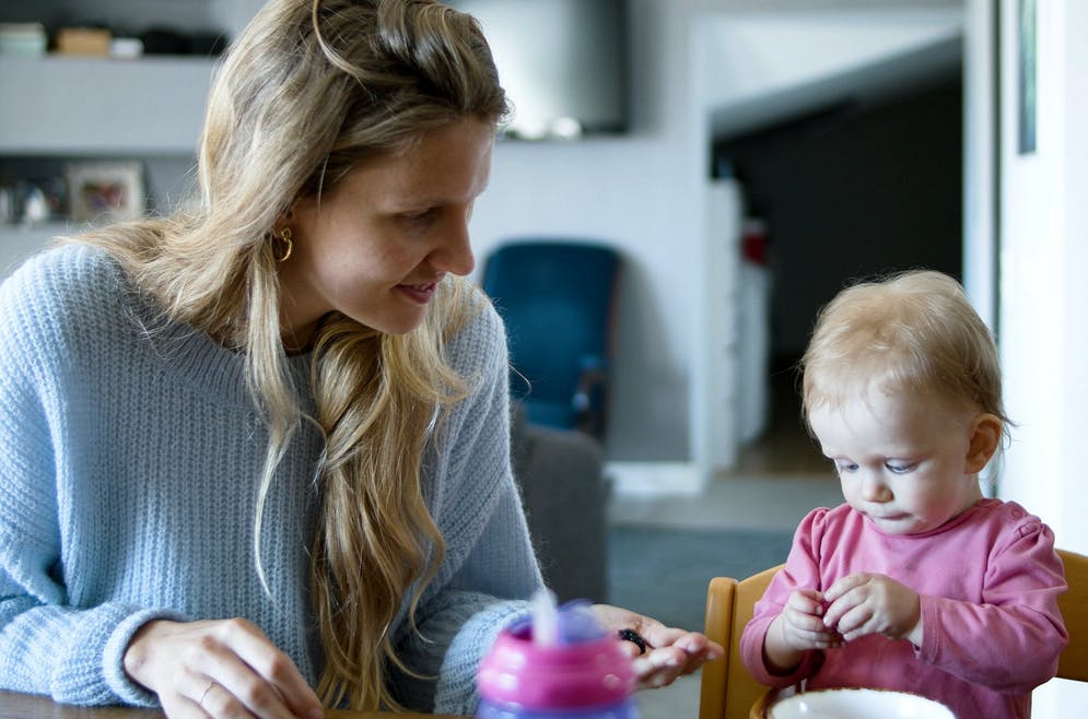 nanny helping a baby with snack time