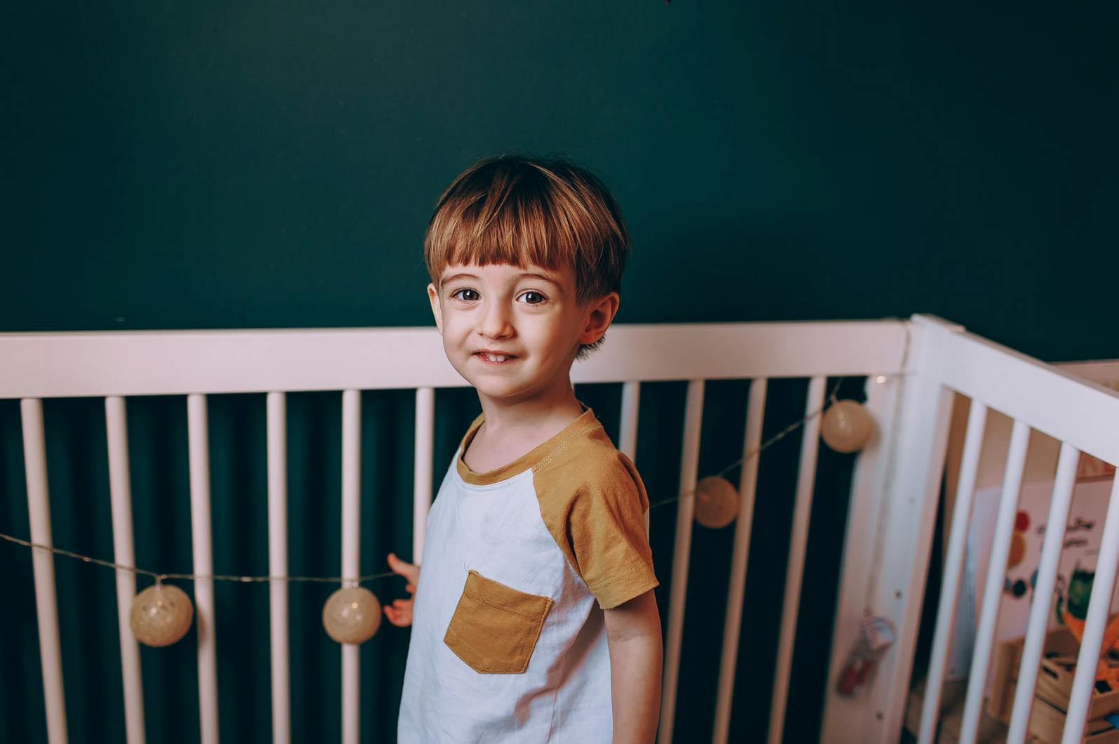 child standing in toddler bed, smiling
