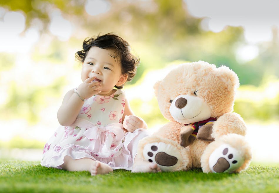 six month old girl sitting with a teddy bear