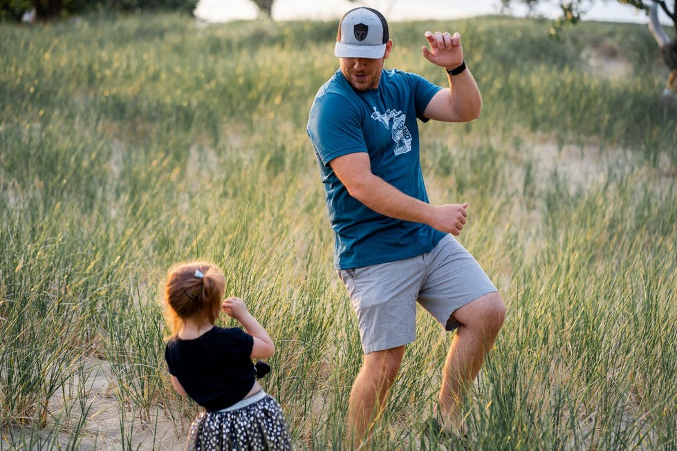 a dad and toddler daughter dancing in a field