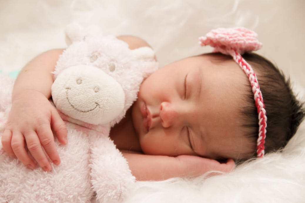 a baby girl sleeping peacefully with a stuffed giraffe