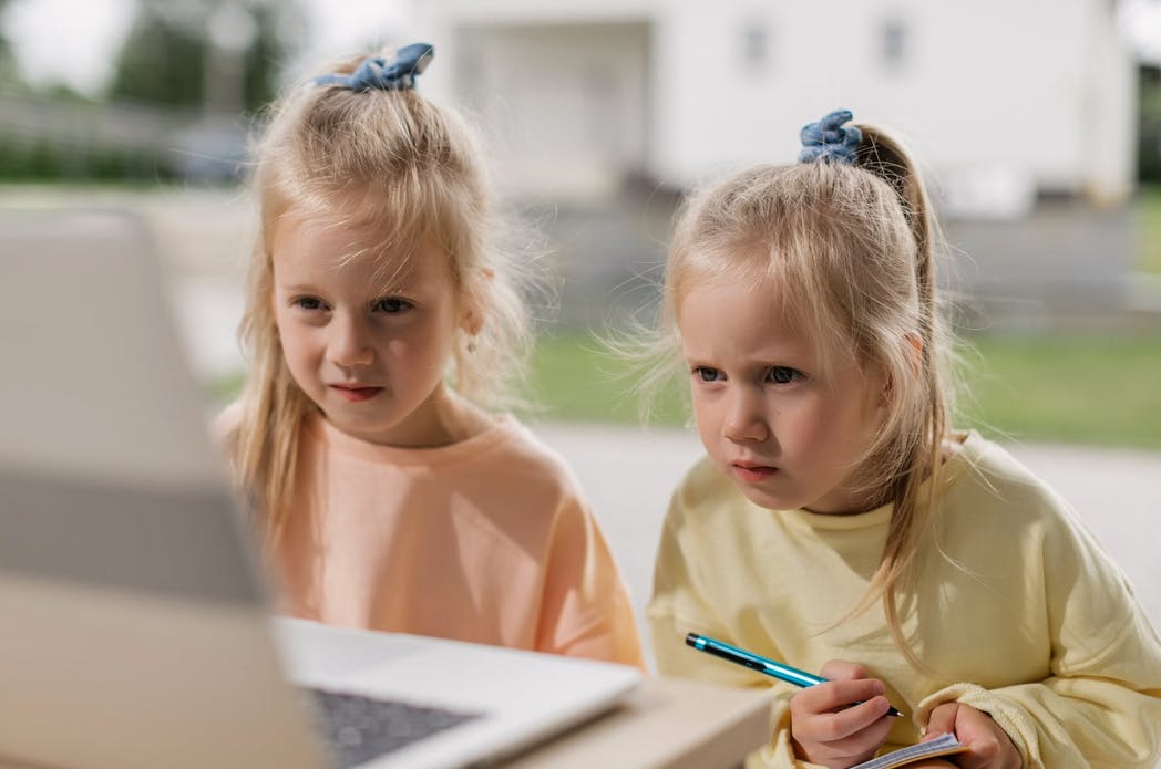twin girls looking at a computer doing homework