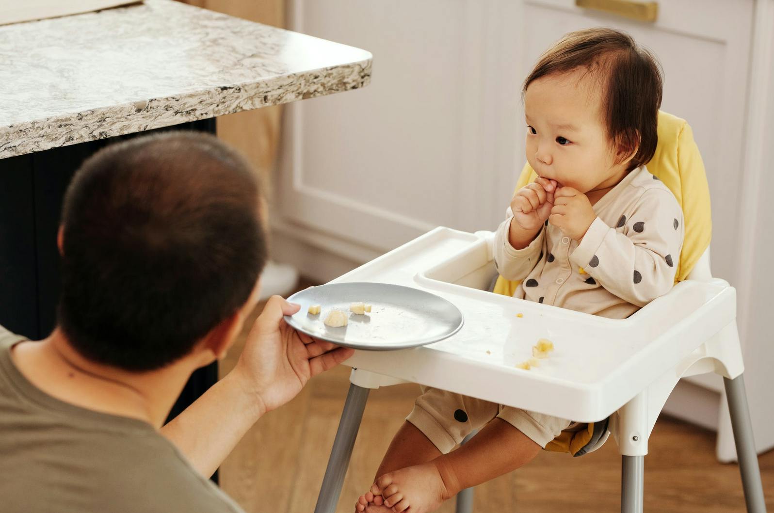 baby sitting in high chair eating food
