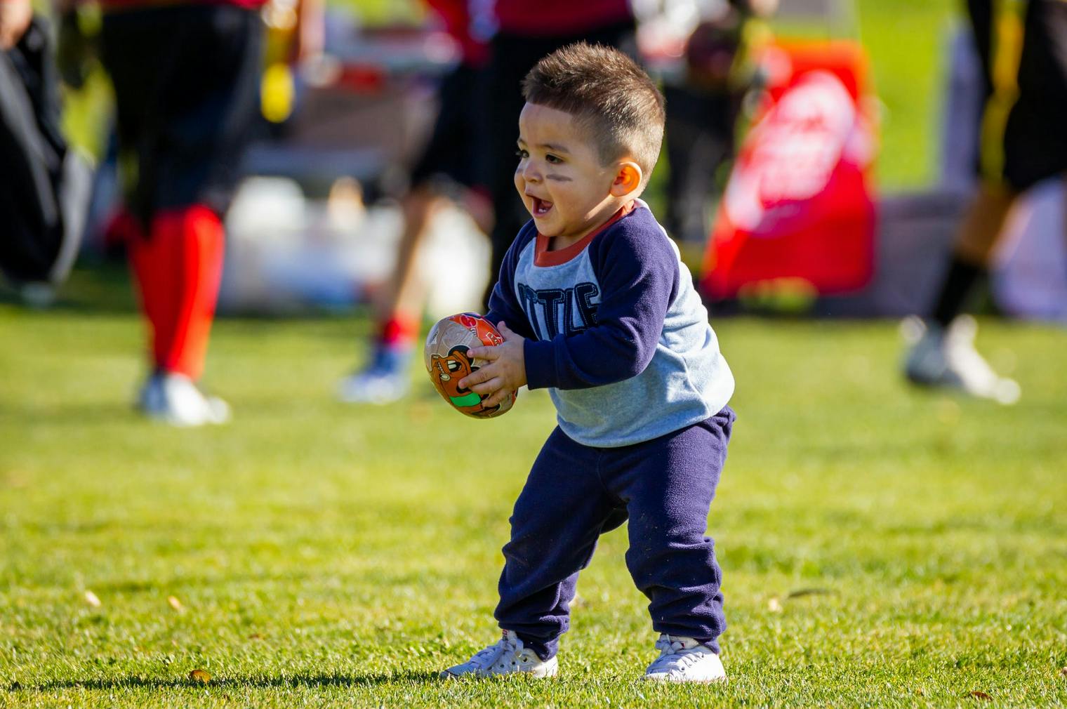 little boy playing with a football in the grass