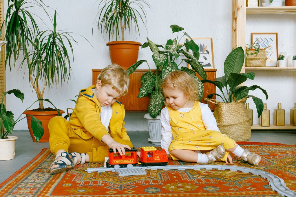 two kids playing with a toy train in a living room