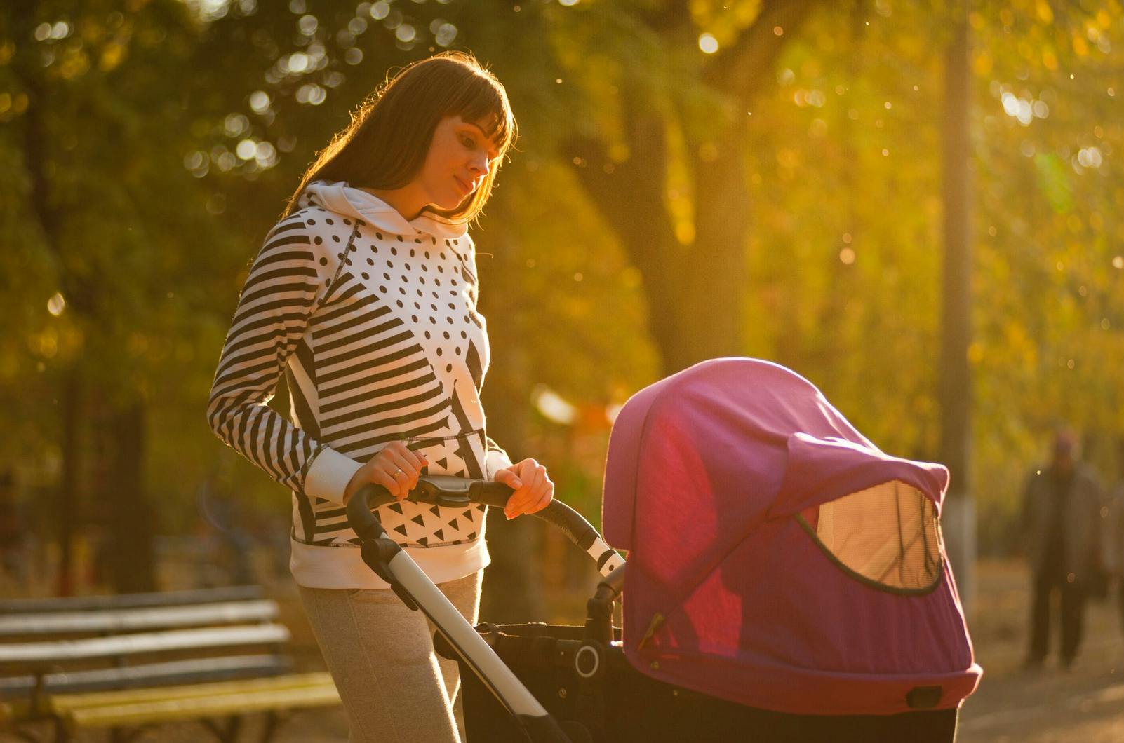 tall mom pushing pink baby stroller in the city