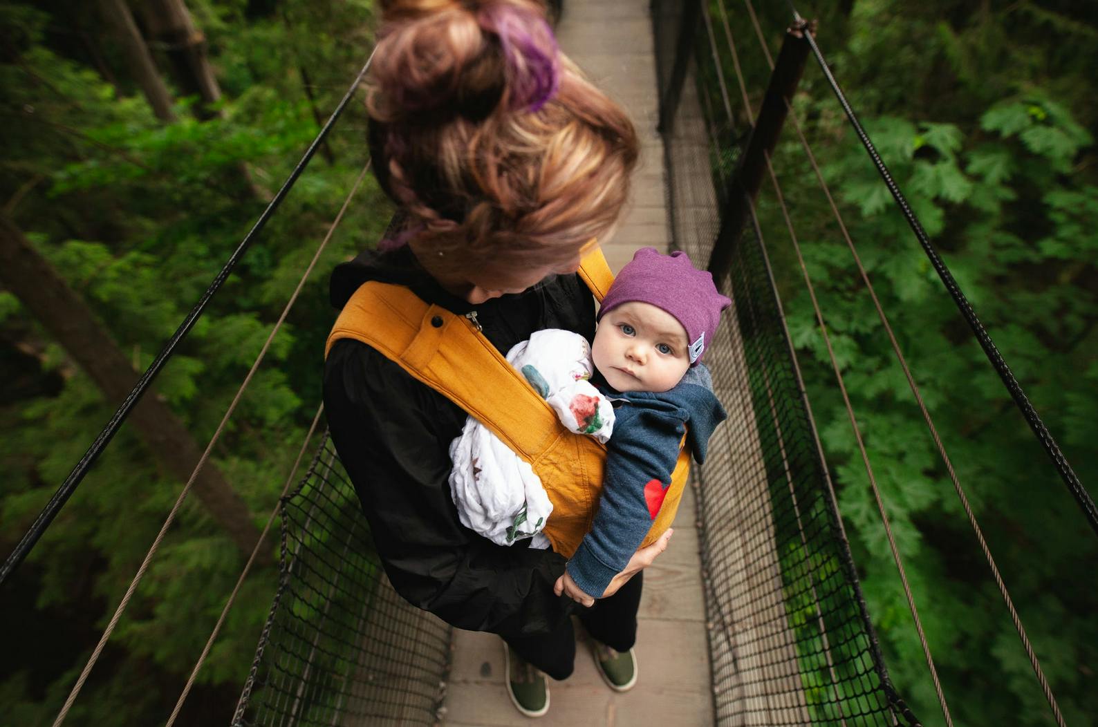 a baby in a baby carrier on a forest bridge